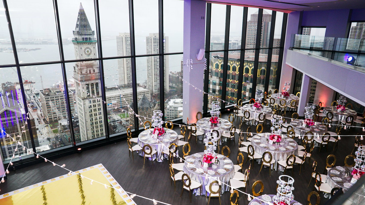 Boston event room with skyline views, custom illuminated centerpieces, gold chairs and coordinated table decor