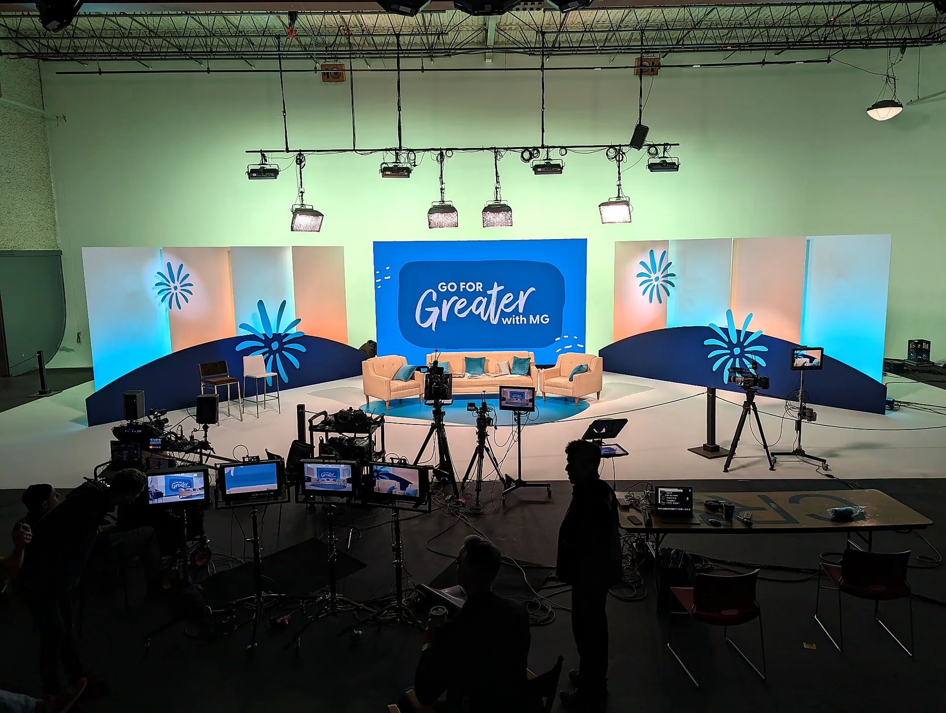 Custom corporate broadcast set with scenic panels, branded graphics, furniture and production cameras