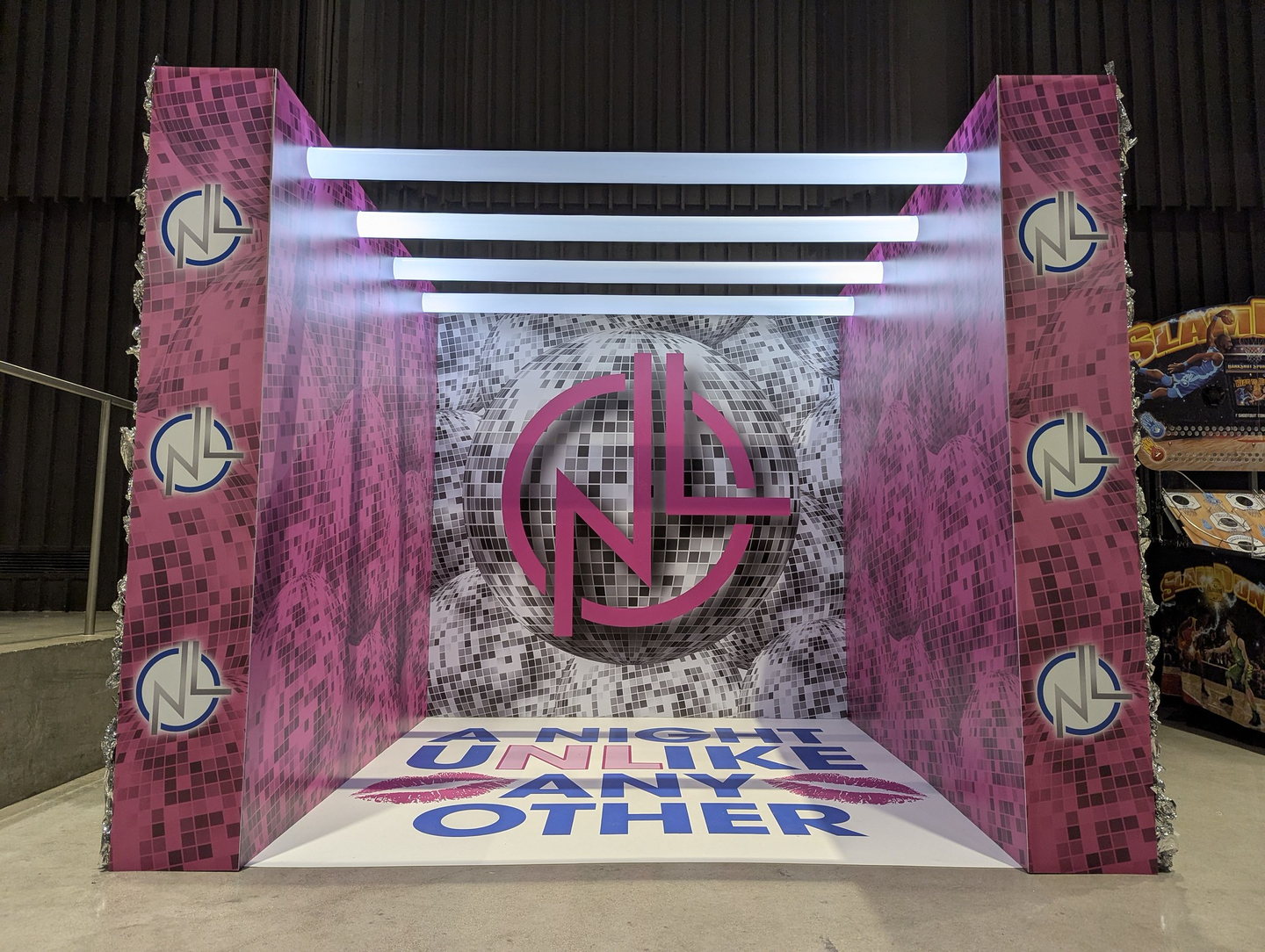 Pink and silver disco-themed custom photo room with dimensional branding and illuminated overhead bars