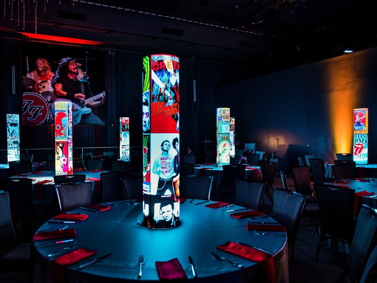 Real corporate event table with custom concert-poster iLLUMITUBES illuminated centerpieces
