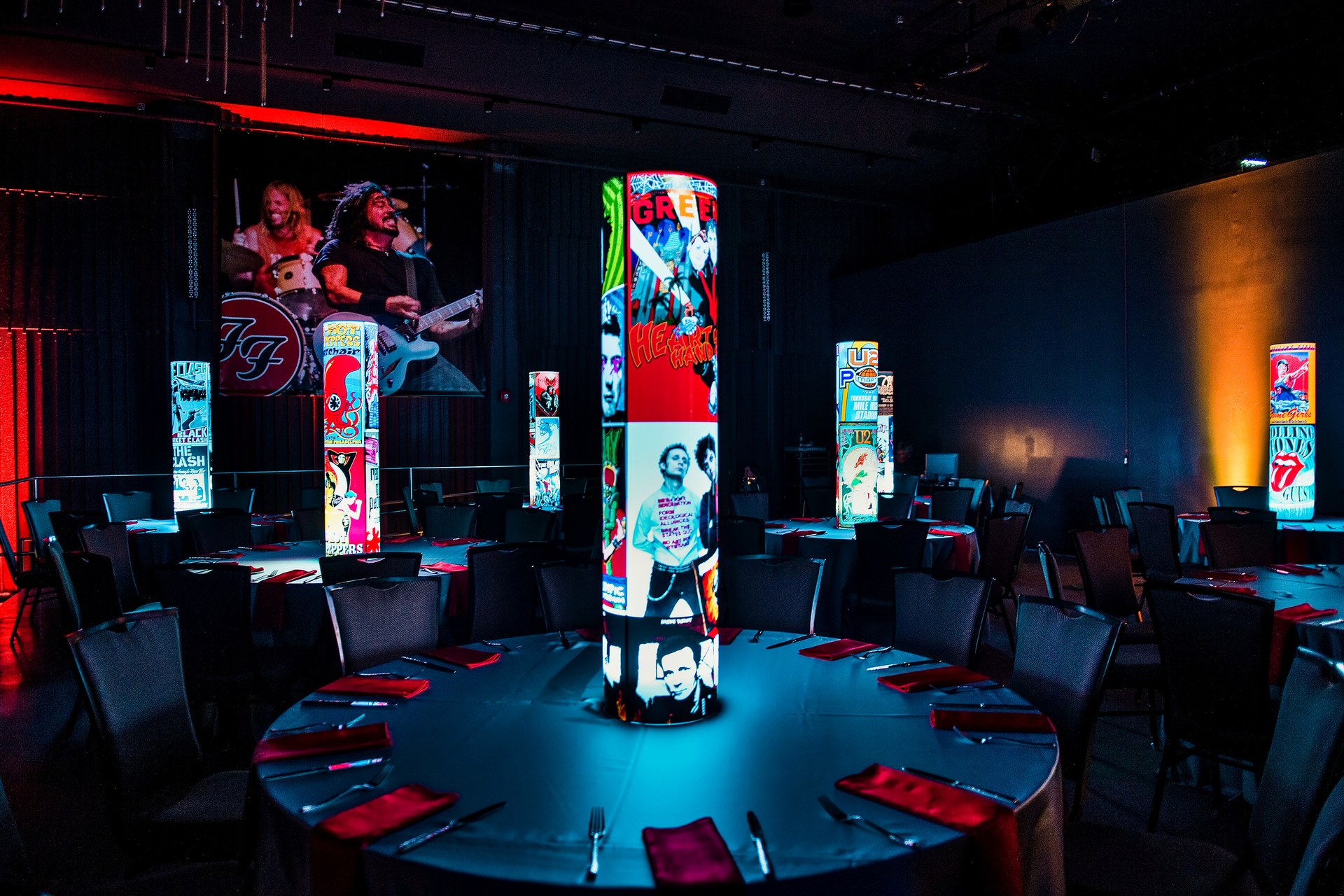 Colorful custom iLLUMITUBES illuminated centerpieces across a branded corporate event room