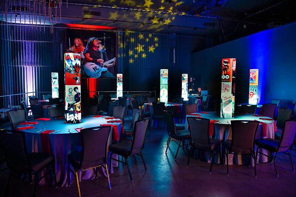 Wide corporate event room with repeated custom iLLUMITUBES illuminated centerpieces
