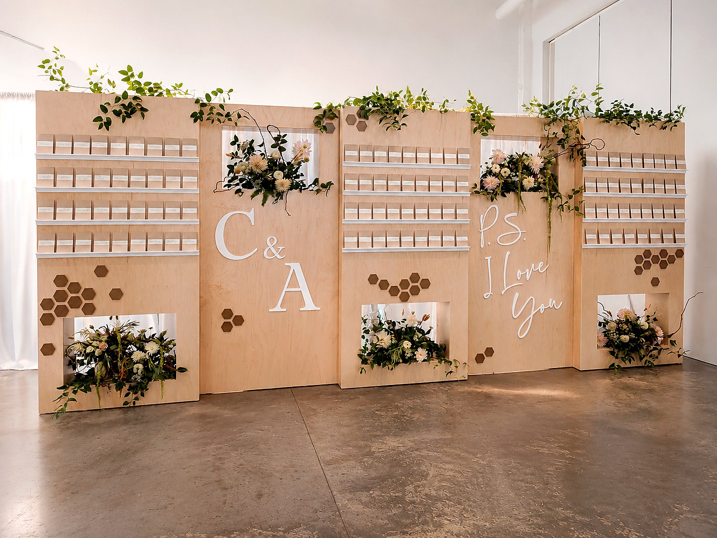 Luxury wedding escort display with natural wood, white lettering, flowers and greenery