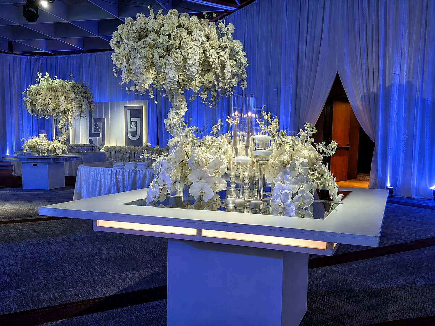Custom illuminated wedding tables with sculptural white floral designs and candlelight