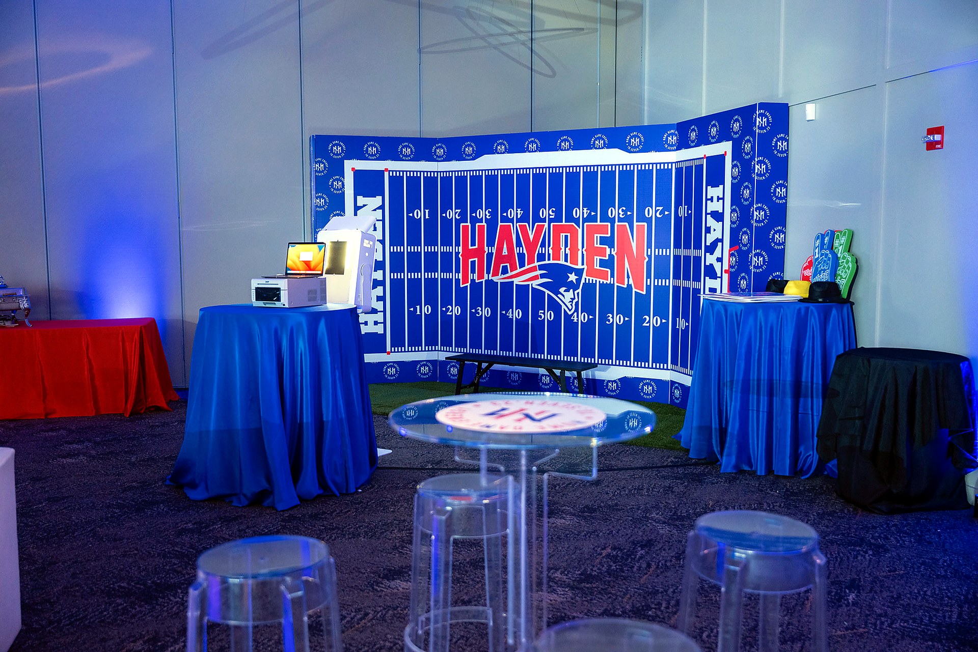 Wide view of a custom football themed bar mitzvah room with photo area and branded scenic backdrop