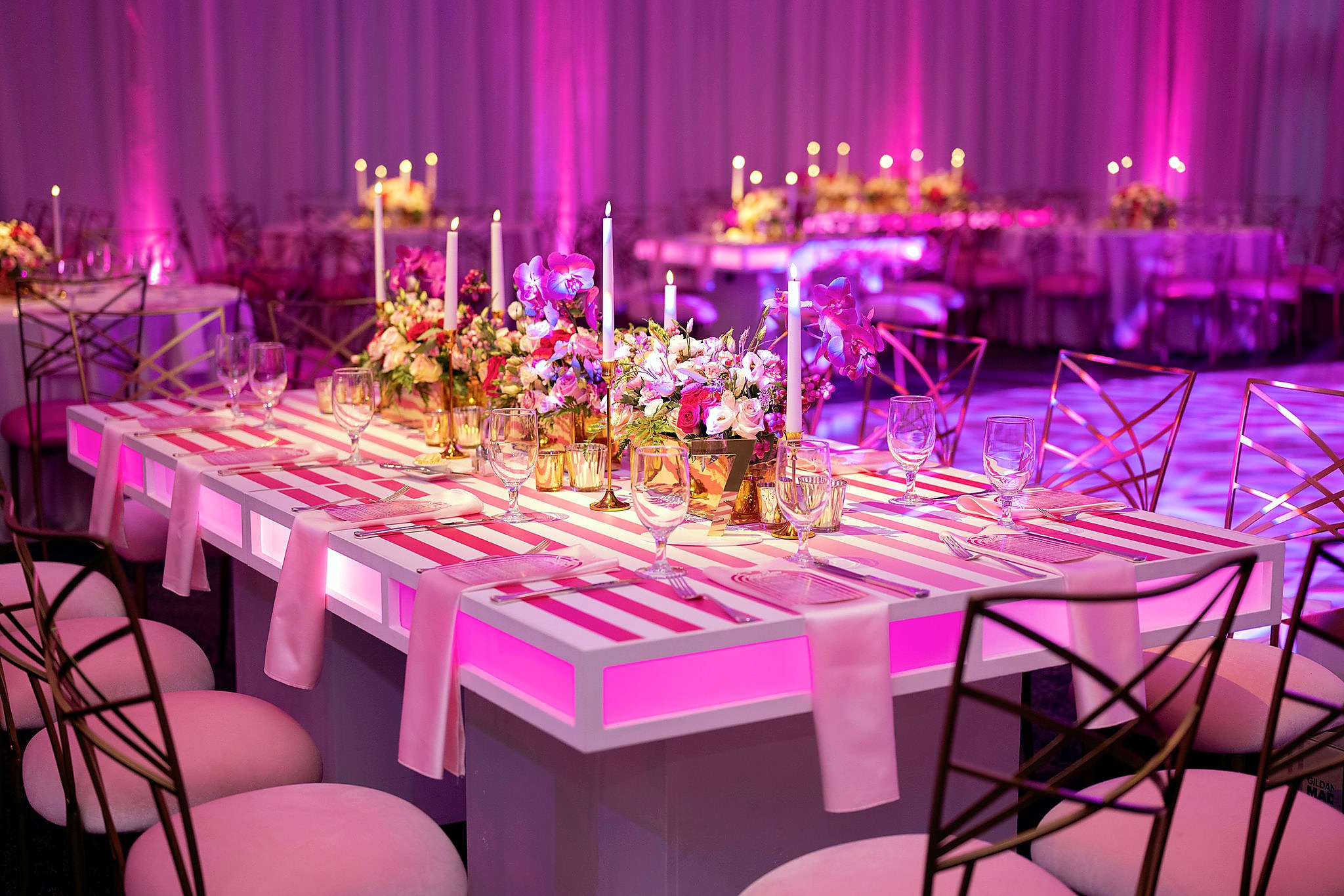 Pink illuminated custom dining tables with floral centerpieces for a high-end mitzvah celebration
