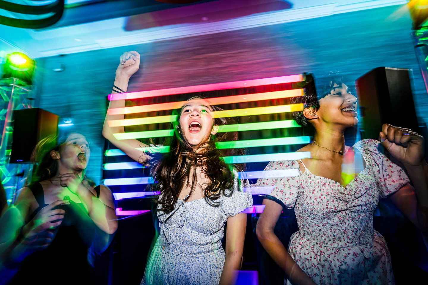 Guests dancing in front of a rainbow illuminated custom DJ surround with event lighting