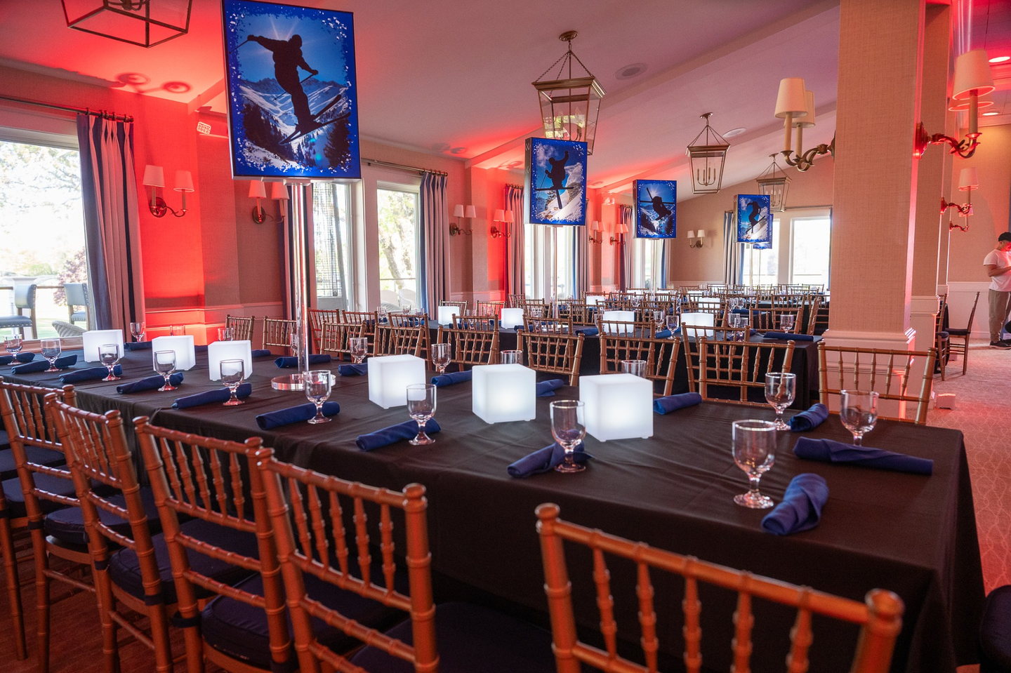 Ski-themed event dining room with custom illuminated centerpieces and warm red uplighting
